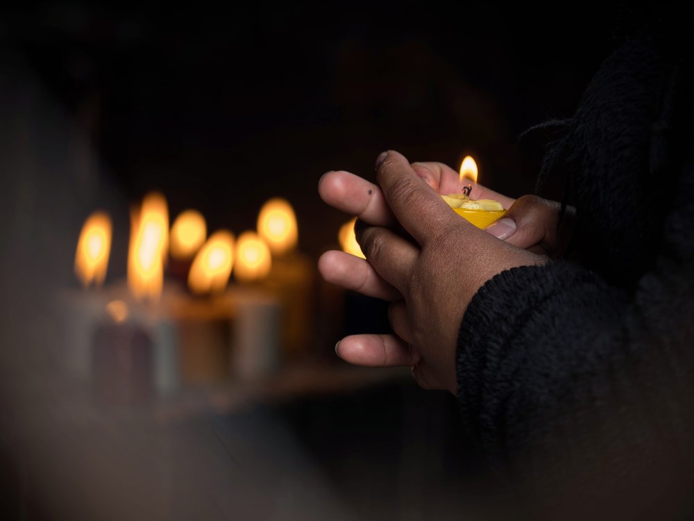 Asian man's hands holding a candle in the dark