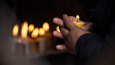 Asian man's hands holding a candle in the dark