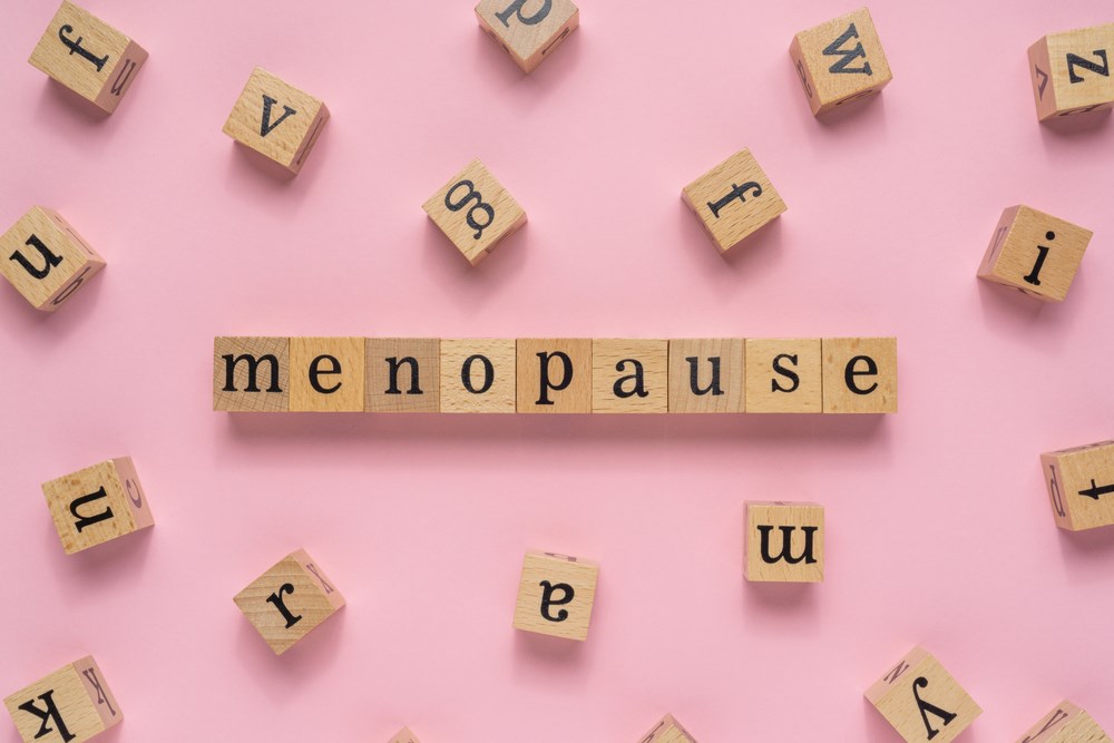 Menopause spelled out in wooden blocks on a pink background