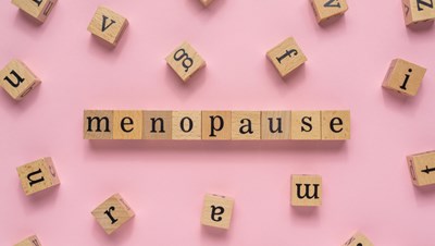 Menopause spelled out in wooden blocks on a pink background