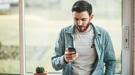 Young man looking at his phone in a light, airy room