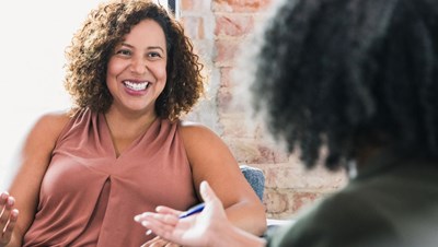 Two women smiling an talking to one another during a therapy session