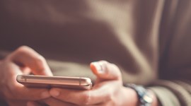 closeup of a person holding a phone in their hands, about to send a text message