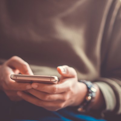 closeup of a person holding a phone in their hands, about to send a text message