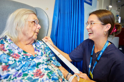 A staff member talking to a patient bedside